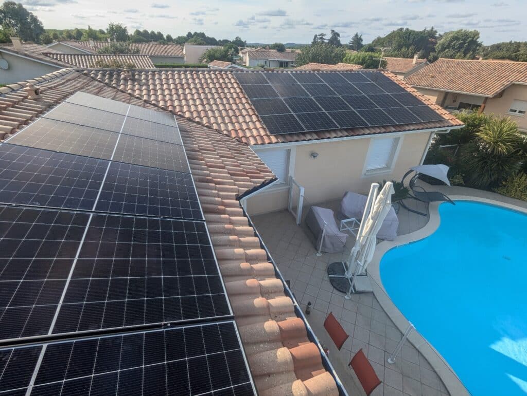 Panneaux solaires intégrés sur toit en tuiles près de la piscine. Panneaux solaires photovoltaïques sur toit de tuiles. Vue aérienne sur piscine bleue, terrasse et mobilier de jardin.